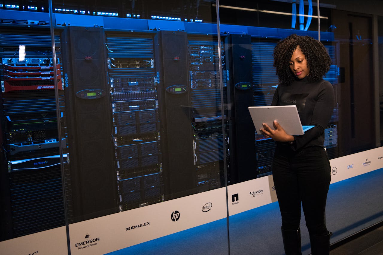 gallery-02 A female engineer using a laptop while monitoring data servers in a modern server room.
